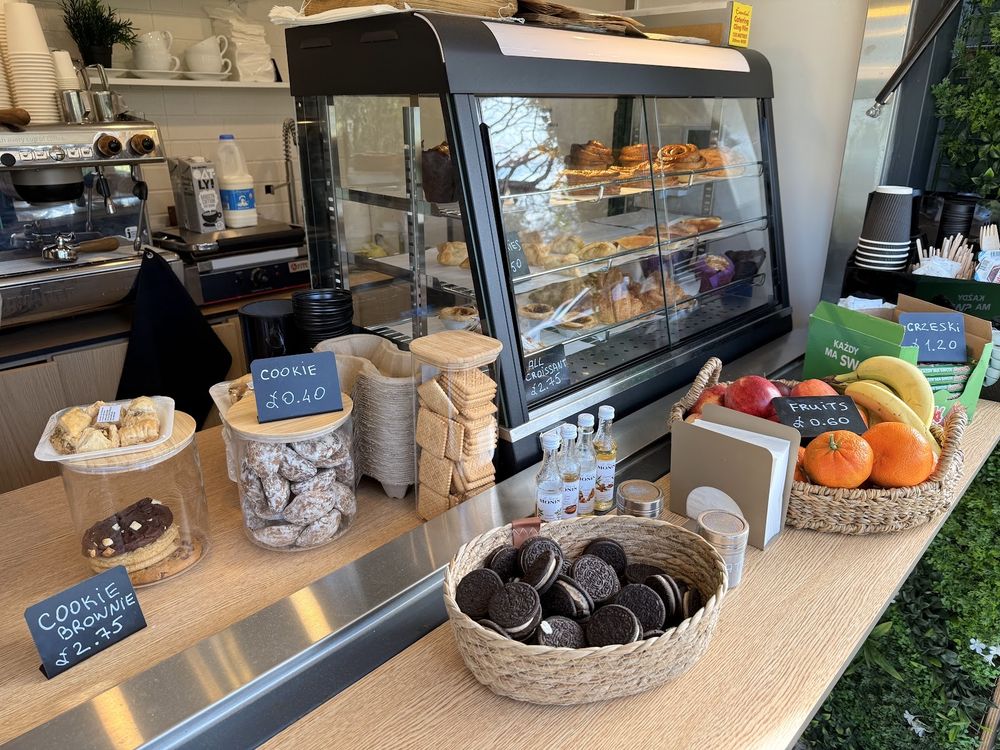 The service counter with the pastry cabinet, cookie jars and a bowl of fruit