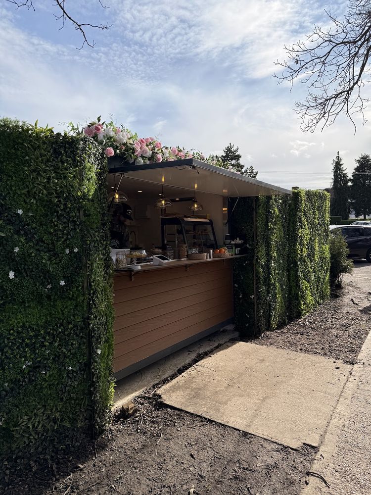 The serving hatch and awning seen head-on from the path, framed by hedges under a blue sky